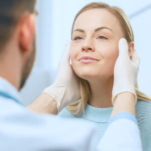 Plastic Cosmetic Surgeon Examines Beautiful Woman's Face, Touches it with Gloved Hands, Inspecting Healed Face after Plastic Surgery with Amazing Results